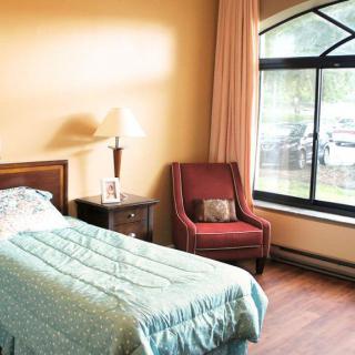 A cozy bedroom with a single bed, a bedside table, and a large window.