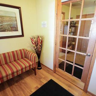 A cozy waiting room with a striped sofa, artwork on the wall, and a glass-paned wooden door.