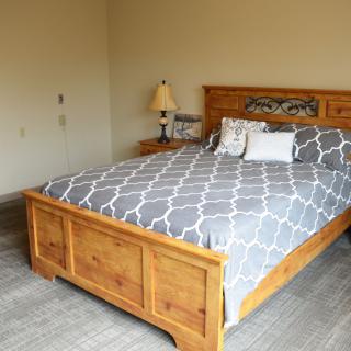 A cozy bedroom with a wooden bed, patterned bedding, and a bedside lamp.