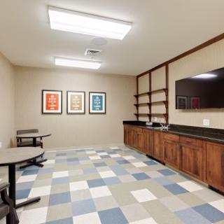 A modern office space featuring a flat-screen TV, shelves, and framed artwork on the walls.