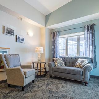 A cozy living room with a sofa and armchair near a large window, featuring stylish decor.