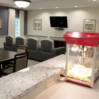 A cozy lounge area with a popcorn machine on the counter and seating facing a television.
