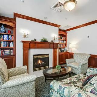 A cozy living room with a fireplace, surrounded by bookshelves and comfortable seating.