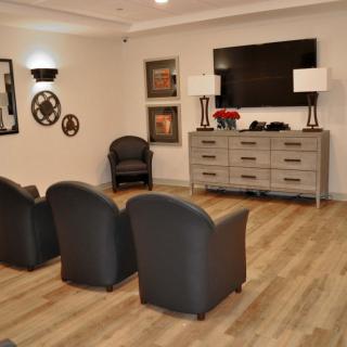 A modern living room setup with comfortable chairs facing a television and decorative wall items.