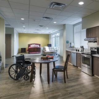 A modern, accessible living space with a kitchen, dining table, and wheelchair.
