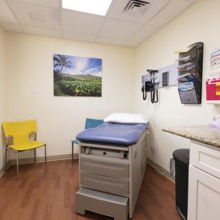 A clean and organized doctor's examination room with medical equipment and seating.