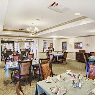 An elegant dining room with neatly arranged tables and chairs, featuring a chandelier and tasteful decor.