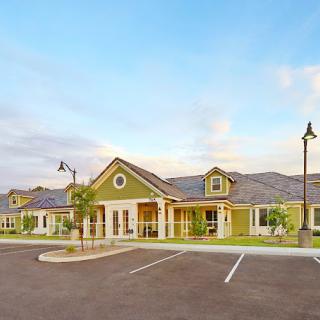 A suburban residential building with a spacious parking lot under a clear sky.