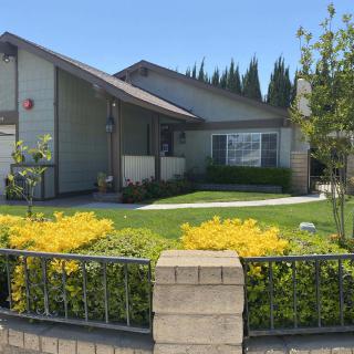 A well-maintained suburban house with a green lawn and garden.