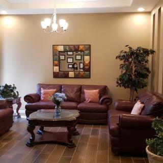 A cozy living room with brown sofas, a coffee table, indoor plants, and decorative artwork.