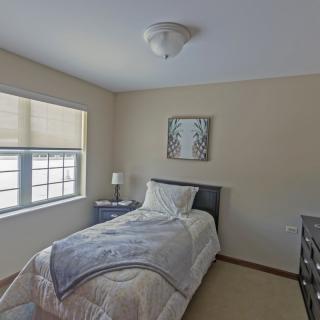 A cozy bedroom with a single bed, window, and decorative wall art.