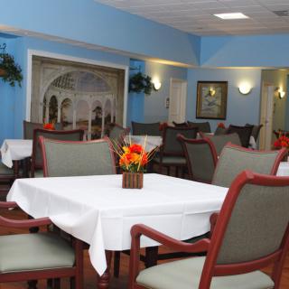 A well-appointed dining area with neatly arranged tables and chairs, featuring floral centerpieces.