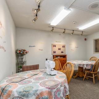 A cozy craft room featuring tables with sewing machines and decorated walls.