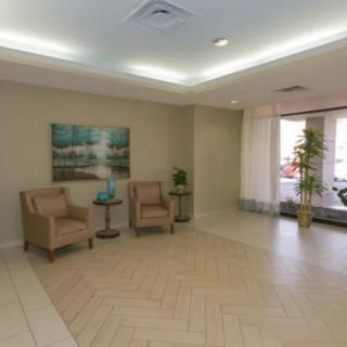 A minimalist waiting area with beige chairs, a painting, and potted plants.
