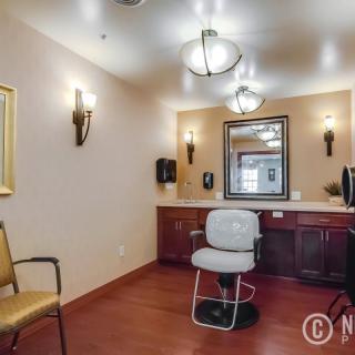 An interior view of a hair salon with a styling chair, mirrors, and warm lighting.