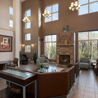 A modern lobby with high ceilings, chandeliers, and a cozy fireplace surrounded by a seating area.