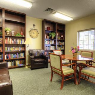 A cozy library room with bookshelves, a reading table, and comfortable seating.