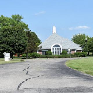 A serene view of a modern building surrounded by greenery under a clear blue sky.
