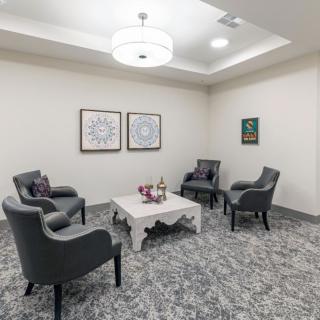 A cozy waiting room with elegant chairs and a coffee table under a modern light fixture.