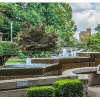 A serene park setting featuring a flowing fountain surrounded by lush greenery.