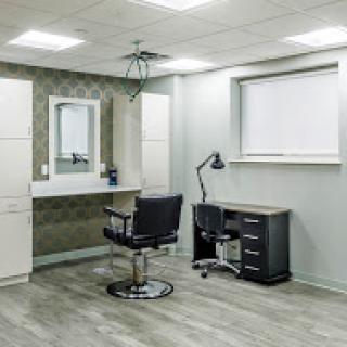 A modern salon interior featuring a barber chair, desk, and mirror.
