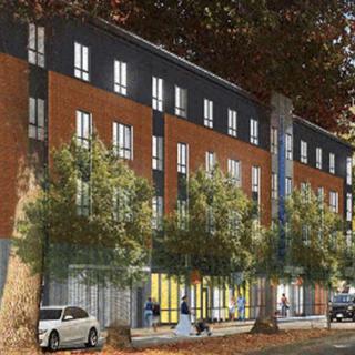 A modern apartment building surrounded by trees and parked cars on a city street.