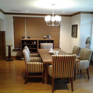 A dining room with a wooden table, striped chairs, and a chandelier overhead.