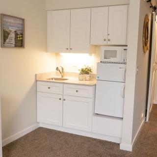 A compact kitchen area with white cabinetry and a microwave, designed for small living spaces.