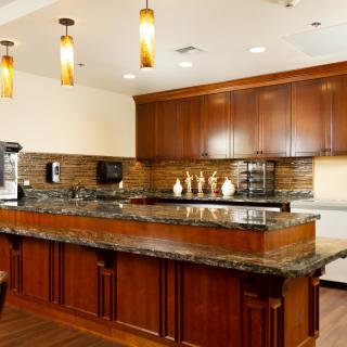 A modern kitchen featuring wooden cabinets, granite countertops, and stylish pendant lighting.