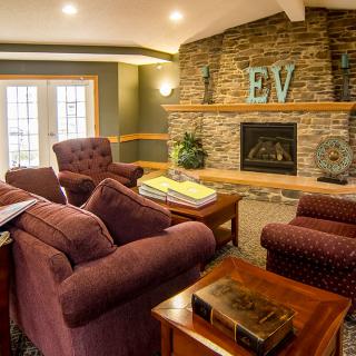 A cozy living room with comfortable armchairs and a stone fireplace.