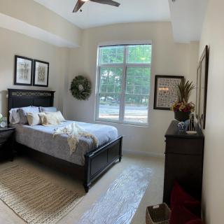 A cozy bedroom with a large window, decorated with tasteful artwork and furniture.