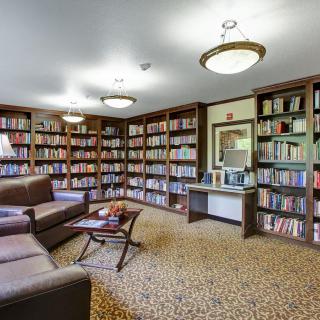 A cozy library with bookshelves, comfortable seating, and warm lighting.