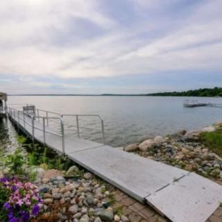 A scenic view of a lake with a dock extending into the water under a clouded sky.