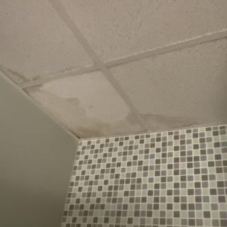 A stained ceiling with water damage above a tiled wall.