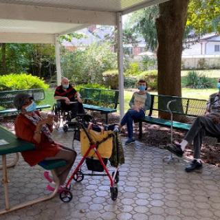 Elderly individuals enjoying a social gathering in a shaded outdoor area.