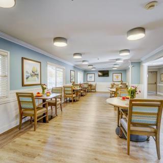 A well-lit dining area with wooden tables and chairs, featuring wall art and comfortable lighting.