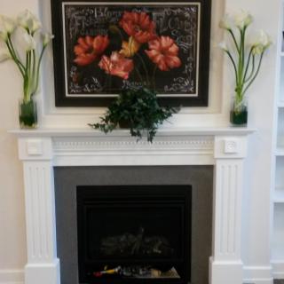 A beautifully decorated fireplace with floral artwork and elegant vases.