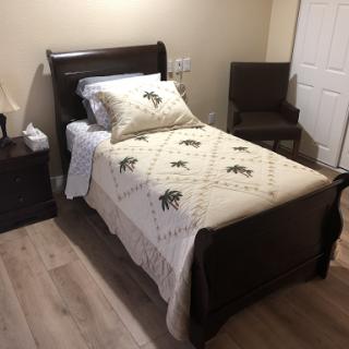 A cozy bedroom featuring a single bed with decorative bedding and a chair.