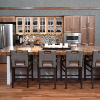 A modern kitchen with a large island and bar stools, featuring wood cabinets and stainless steel appliances.