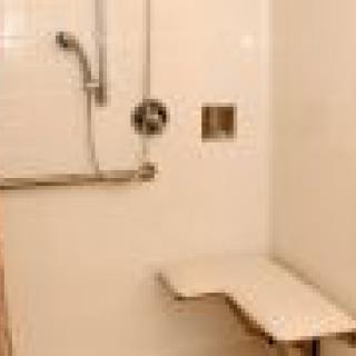 An accessible shower featuring a foldable seat and grab bar.