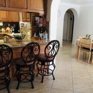 A cozy kitchen with bar stools, wooden cabinets, and a view into the dining area.