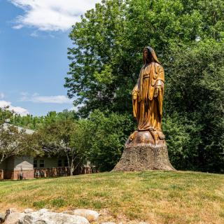 A large statue set in a natural landscape with lush greenery in the background.