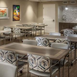A well-lit conference room with tables and patterned chairs, adorned with colorful artwork on the walls.