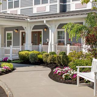 A charming house with a welcoming front porch and beautiful garden landscaping.