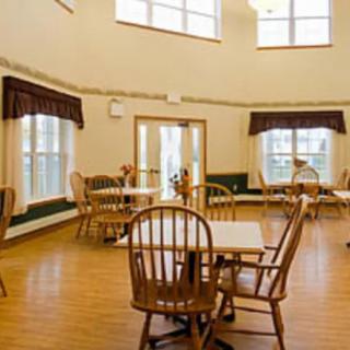 A bright and spacious dining room with wooden tables and chairs, surrounded by large windows.