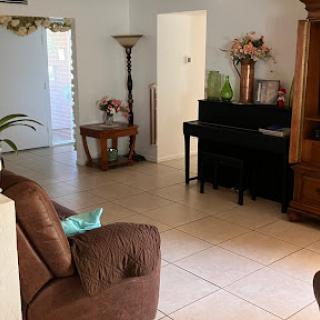 A cozy living room featuring a piano, comfortable seating, and decorative elements.