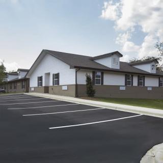 A view of a residential building with an empty parking lot on a clear day.