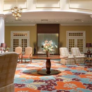 A spacious hotel lobby with elegant furniture and a colorful carpet.