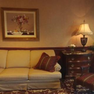 A cozy living room with a sofa, lamp, and decorative painting.