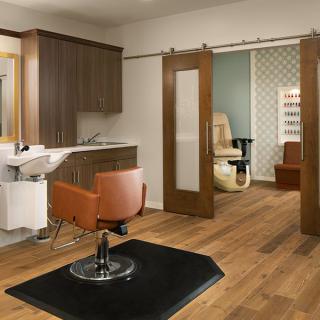 A modern salon interior with a hairdressing station and sliding doors leading to a private room.
